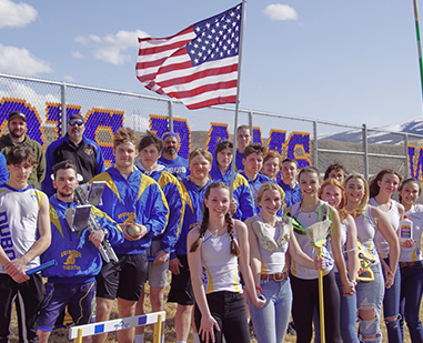 Students on bleachers next to United States flag