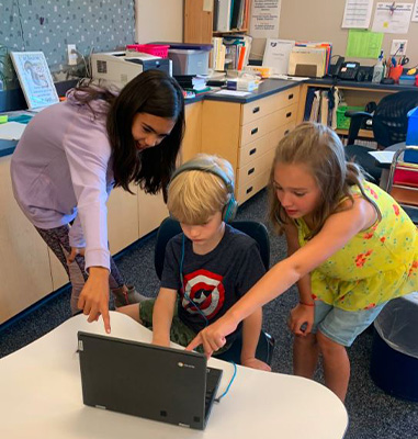 Three students looking at a laptop