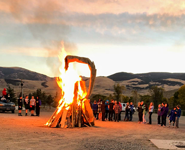 An object burns as onlookers watch