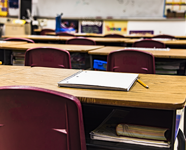 Empty classroom with a desk and notebook