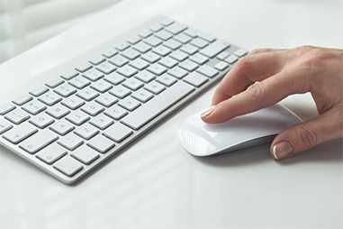 A hand moving mouse next to the keyboard